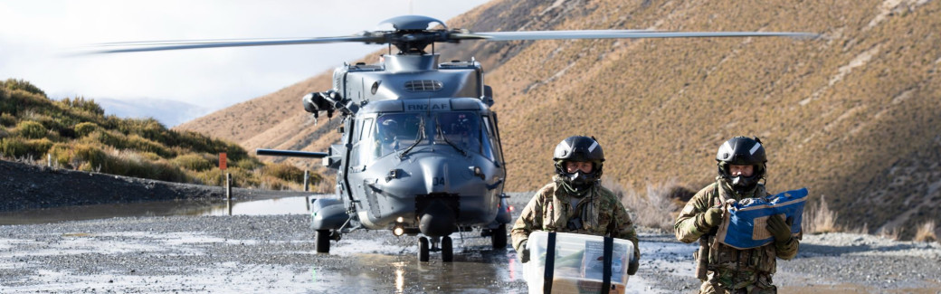 Two NZDF personnel holding supplies