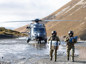 Two NZDF personnel holding supplies